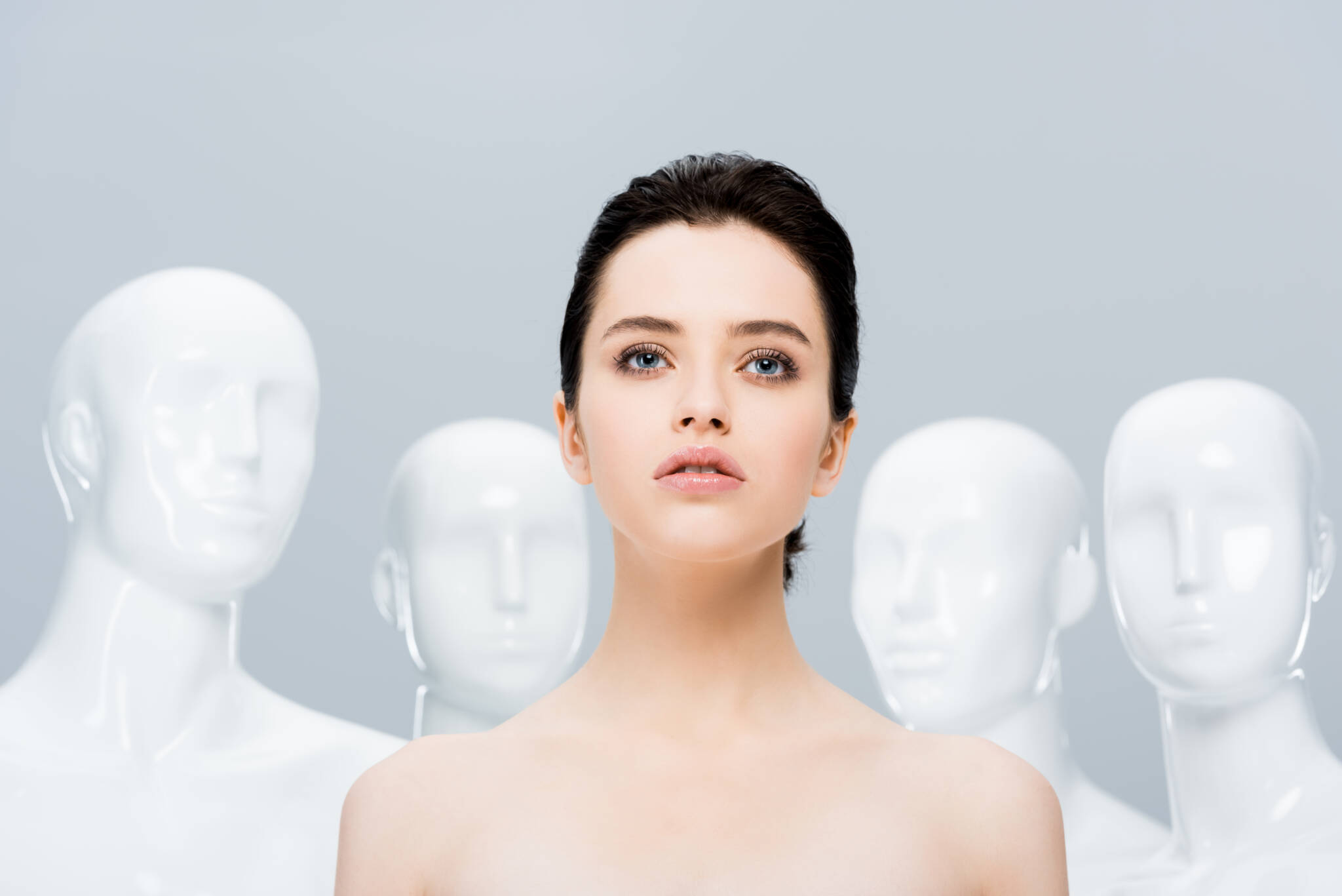 Woman with short dark hair and blue eyes standing in front of four mannequins