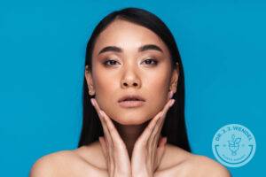 Photo of a beautiful young woman posing isolated over blue wall background.