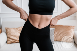 woman showing slim midriff while wearing a sports bra and yoga pants